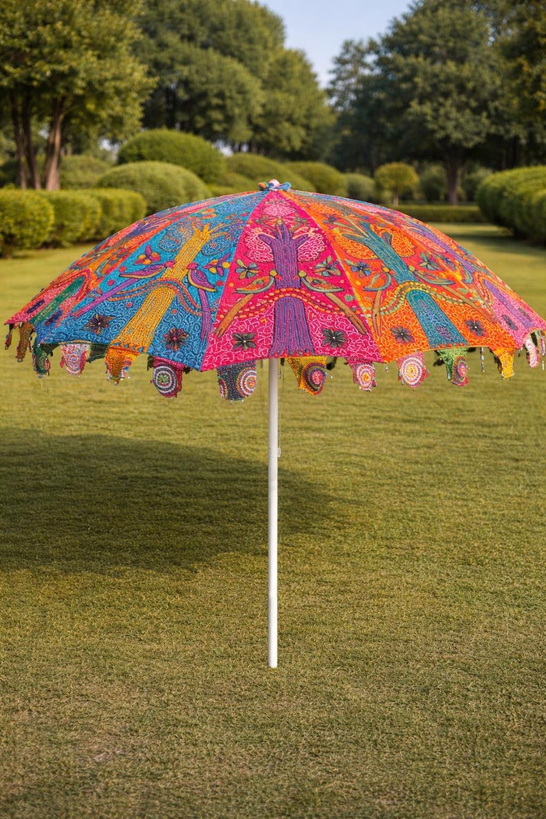 May include: A vibrant, colorful outdoor umbrella with a white pole. The umbrella's canopy features intricate patterns in shades of pink, blue, orange, and yellow. The edges are adorned with decorative tassels.