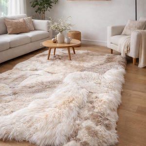 Op de afbeelding: Een groot, rechthoekig vloerkleed met een dikke, hoogpolige structuur in een natuurlijk, meerkleurig palet van crème, beige en lichtbruin. Het kleed heeft een zachte, getextureerde uitstraling met lange vezels die een gelaagd effect creëren.