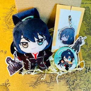 Peut inclure: Une poupée en peluche aux cheveux bleus et une cravate rouge, ainsi qu'un porte-clés, un bouton et des autocollants, tous avec des illustrations de personnages de style anime. Les articles sont disposés dans une boîte en carton.