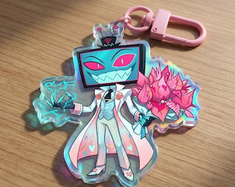 May include: A holographic acrylic keychain featuring a cartoon character with a TV screen head, holding a bouquet of pink flowers. The character wears a white suit with pink accents and a pink clasp.