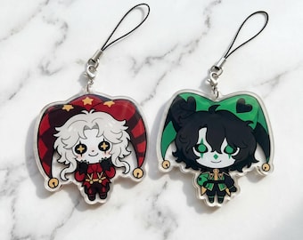 May include: Two acrylic charms featuring cartoon jester characters. The left charm has a white-haired figure in a red and black jester hat with gold stars. The right charm shows a dark-haired figure in a green and black jester hat with hearts.