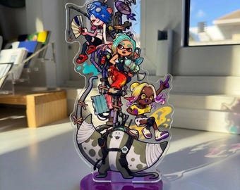 以下が含まれることがあります： Splatoonのビデオゲームシリーズに登場する4人のアニメキャラクターのカラフルなイラストが描かれた透明なアクリルスタンド。土台には大きなマンタが描かれており、展示用の紫色の円形ベースに取り付けられています。