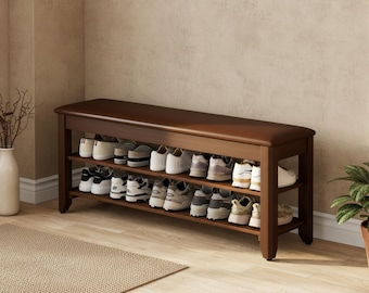 Op de afbeelding: Een donkerbruine houten schoenenrek met een gewatteerde bovenkant, met twee planken gevuld met diverse schoenen. De bank staat tegen een lichtgekleurde muur, met een neutraal tapijt op de voorgrond.