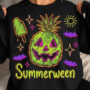 May include: A black long-sleeve sweatshirt featuring a neon green and pink graphic of a pineapple jack-o'-lantern, a popsicle, bats, stars, and a sun. The text "Summerween" is printed in yellow at the bottom of the graphic design on the front.