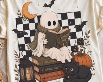 May include: An off-white t-shirt featuring a graphic of a ghost wearing a scarf and reading a book titled Midnight Tales. The design includes a black and white checkered background, a crescent moon, bats, a lantern, a pumpkin, and a black cat.