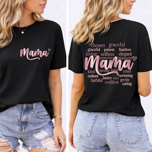 Puede incluir: Camiseta negra con la palabra "Mama" en fuente rosa en la parte delantera. La parte posterior de la camiseta presenta la palabra "Mama" en una fuente rosa más grande, rodeada de palabras como "elegida", "graciosa" y "amorosa".