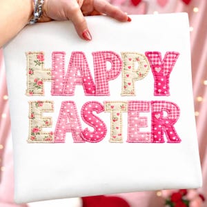 Peut inclure: Un tissu blanc avec les mots "HAPPY EASTER" appliqués en tissu rose et crème. Les lettres sont dans un style patchwork, avec des motifs floraux, à pois et à carreaux. Le tissu est tenu par une main.