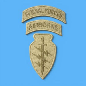 Może przedstawiać: Zestaw trzech haftowanych naszywek w kolorze piaskowym. Górna zakrzywiona naszywka ma napis SPECIAL FORCES, środkowa AIRBORNE, a dolna naszywka w kształcie tarczy przedstawia pionowy sztylet z trzema poziomymi błyskawicami nałożonymi na niego.