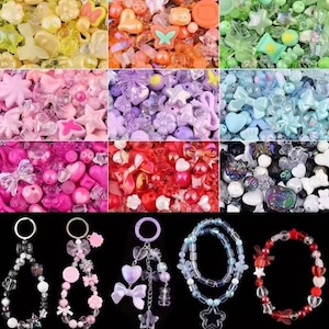 May include: A collection of colorful beads and charms in various shapes, including hearts, stars, and bows. The image also shows beaded keychains and bracelets in shades of pink, blue, and red. The beads are made of plastic and glass.