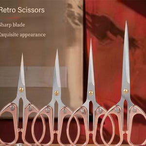 Könnte beinhalten: Eine Reihe von roségoldenen Scheren mit silbernen Klingen. Die Scheren haben ein Retro-Design und werden vor einem verschwommenen Hintergrund präsentiert. Der Text auf dem Bild lautet "Retro Scissors", "Sharp blade" und "Exquisite appearance".