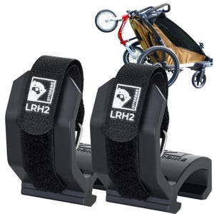 May include: Two black Otterbike LRH2 bike trailer attachments with Velcro straps. Each attachment has a white logo with an otter and the text "OTTERBIKE" and "LRH2". A tan and black bike trailer is in the background.