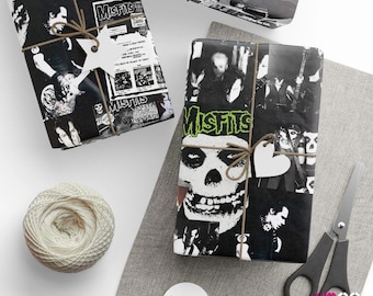 Puede incluir: Regalos envueltos con papel de regalo en blanco y negro con temática de la banda Misfits. Los regalos están atados con hilo y adornados con etiquetas blancas. También se ven una madeja de hilo, unas tijeras y una etiqueta en blanco.