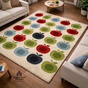 Op de afbeelding: Een rechthoekig vloerkleed met een crèmekleurige achtergrond en een herhalend patroon van gestileerde appels in rood, groen, blauw en zwart. Het vloerkleed is gemaakt van zacht, getuft materiaal.