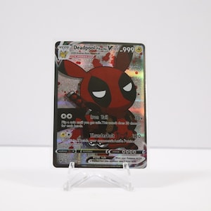 May include: A collectible trading card featuring a Deadpool-themed Pikachu character. The card has a red and black color scheme with the text "Deadpool" and "V". The card is displayed on a clear plastic stand.