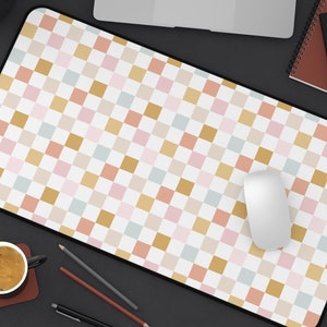 May include: A checkered mouse pad with a white background and squares in shades of pink, beige, and light blue. A white computer mouse is on the pad.