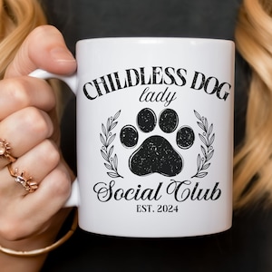 May include: White ceramic mug with black text that reads "Childless Dog Lady Social Club Est. 2024". A black paw print is in the center of the mug.