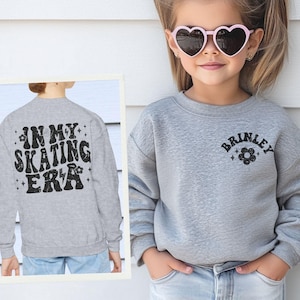 May include: A gray sweatshirt with the text "In My Skating Era" on the back and the name "Brinkley" with a flower on the front.