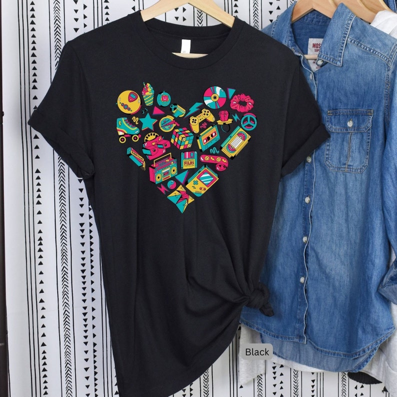 May include: Black t-shirt with a heart-shaped design featuring a variety of 80s and 90s icons, including roller skates, cassette tapes, a boombox, a Rubik's cube, and a video game controller.