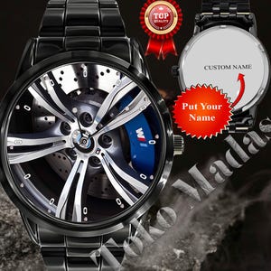 May include: Black wristwatch with a unique face design featuring a car wheel with blue accents and the text "W". The watch has a black metal band and a round face. The back of the watch has the text "CUSTOM NAME".