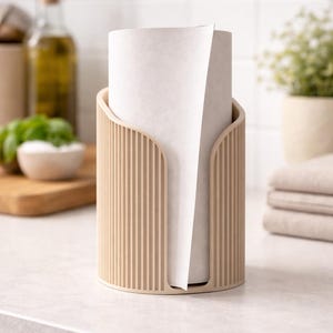 Op de afbeelding: Een cilindrische keukenrolhouder in een lichtbeige kleur met een verticale geribbelde textuur. De houder is voorzien van een U-vormige uitsparing aan de voorzijde, waardoor de witte keukenrol die erin zit gemakkelijk toegankelijk is.