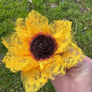 May include: A yellow lace sunflower with a brown center. The sunflower is handmade and would be a great addition to a home decor collection.