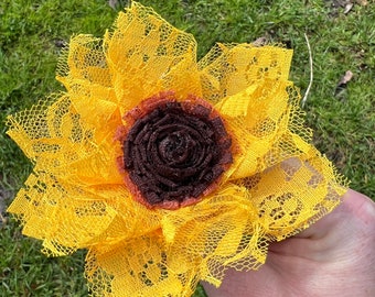 May include: A yellow lace sunflower with a brown center. The sunflower is handmade and would be a great addition to a home decor collection.