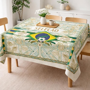 May include: A rectangular tablecloth with a Brazilian flag design. The tablecloth features the word "SELE&Ccedil;&Atilde;O" in gold lettering, a soccer ball, and the words "CANARINHO SPIRIT" and "THE LAND OF SAMBA". The color scheme includes green, yellow, and white.