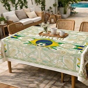May include: A rectangular tablecloth with a Brazilian theme. The design features the Brazilian flag, a soccer ball, and the words "SELECAO", "CANARINHO SPIRIT", and "THE LAND OF SAMBA". The tablecloth has a white background with green and gold accents.