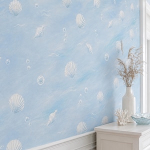 Peut inclure: Papier peint bleu clair avec un motif répétitif de coquillages et de bulles blancs. Le design présente une texture peinte avec des coups de pinceau visibles. Un vase blanc avec des herbes séchées et un corail blanc sont au premier plan.