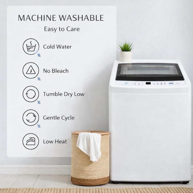 May include: A white top-load washing machine with a black control panel. A woven laundry basket with a white towel is in front of the machine. Text on a sign indicates the machine is machine washable and easy to care for.