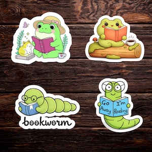 May include: Four whimsical stickers featuring cartoon animals reading books. A green frog in a hat, a frog on a log, a bookworm, and a worm with glasses holding a book that says "Go Away I'm Reading".