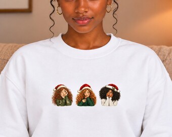 Può includere: Una felpa bianca a girocollo con una stampa grafica di tre figure illustrate che indossano cappelli da Babbo Natale rossi e bianchi. Le figure sono affiancate, ognuna con le mani vicino al viso, e indossano maglioni invernali lavorati.