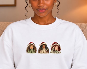 Può includere: Una felpa bianca a girocollo con una stampa centrale raffigurante tre figure illustrate che indossano cappelli da Babbo Natale rossi e bianchi. Ogni figura ha un'espressione sorpresa con le mani vicino al viso e indossa maglioni invernali.