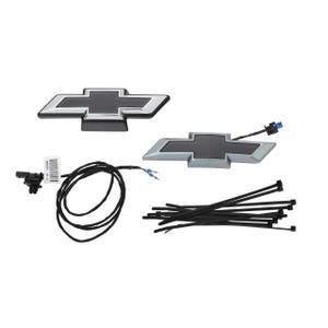 May include: Two Chevrolet emblem car parts, one black and silver, the other silver and black. Also included are black zip ties, wiring, and a small connector. Automotive parts.