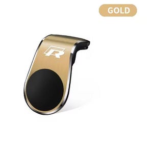 以下が含まれることがあります： 黒い円形の磁石部分が付いた、金色の車の電話マウント。 マウントは湾曲したデザインで、シルバーの「R」ロゴが付いています。「GOLD」の文字が金色の長方形で表示されています。