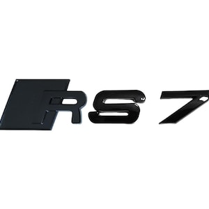 May include: Black RS7 emblem set. The emblem features the letters "RS" in a stylized font, followed by the number "7". The letters and number are glossy and appear to be made of a durable material.