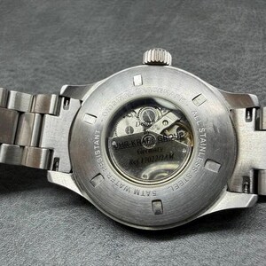 May include: A stainless steel wristwatch with a metal link bracelet, featuring an exhibition case back that reveals the internal mechanical movement. The back is engraved with UHR-KRAFT GROUP, Germany, Ref 17022/2AM, 5ATM WATER RESISTANT.