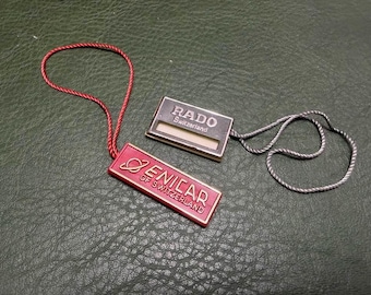 2 etiquetas colgantes vintage sin usar para relojes Enicar y Rado.