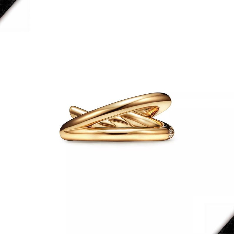 K&ouml;nnte beinhalten: Ein goldfarbener Ohrklemme mit einem einzigartigen, flie&szlig;enden Design. Die Manschette umschlie&szlig;t das Ohr und hat an einem Ende einen kleinen, funkelnden Akzent. Das Schmuckst&uuml;ck ist vor einem sauberen, wei&szlig;en Hintergrund platziert.