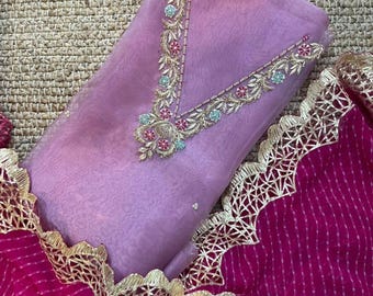 May include: A lavender fabric piece featuring a V-shaped neckline with intricate floral embroidery in pink, blue, and gold thread, paired with a magenta fabric featuring thin white stripes and a wide, scalloped gold metallic lace border trim.