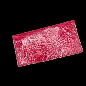 May include: A red wallet with a textured, crocodile-like pattern. The wallet is rectangular and appears to be made of leather or a similar material. The color is a vibrant, deep red.