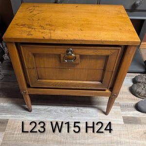 May include: A vintage wooden nightstand with a drawer and a metal handle. The nightstand is a warm brown colour and has a rectangular shape. The dimensions are L58 W38 H61 cm.