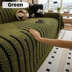 Könnte beinhalten: Grüne Sofahusse mit strukturiertem Muster und schwarzen Akzenten. Die Hülle ist über ein Sofa drapiert, mit dekorativen Kissen und einer Teetasse sichtbar. Das Wort "Green" befindet sich in einem weißen Oval oben links.