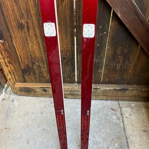 May include: A pair of red cross-country skis with black bindings and the word "CHASE" printed in white on each ski. The skis are 215 cm long.