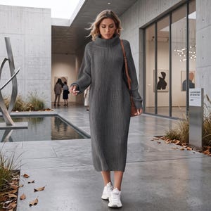 Può includere: Un abito in maglia color grigio antracite di lunghezza midi con trama a coste, collo alto a lupetto e maniche lunghe. Il capo è abbinato a scarpe da ginnastica bianche e a una borsa a tracolla in pelle marrone con cinturino sottile.