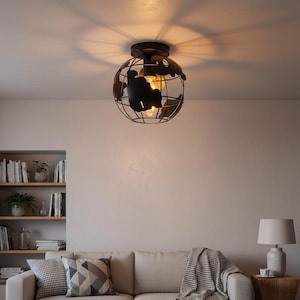 Peut inclure: Un plafonnier noir en forme de globe. Le luminaire présente un design en cage métallique avec des découpes représentant les continents. Une ampoule est visible à l'intérieur. Le luminaire est monté sur un plafond blanc, projetant une ombre.