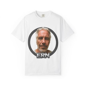 Puede incluir: Camiseta blanca con un retrato de un hombre con pelo gris y barba, enmarcado por un círculo gris oscuro. Las letras "ERN" se muestran en una fuente metálica en 3D debajo del retrato.