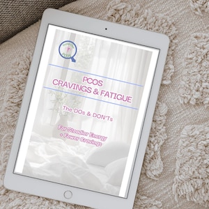 May include: A white tablet displaying a document titled "PCOS CRAVINGS & FATIGUE" with the text "The DOs & DON'Ts" and "For Steadier Energy + Fewer Cravings." The tablet is resting on a textured, beige surface.