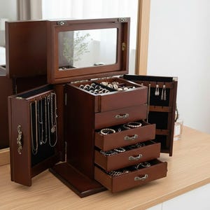 May include: A dark brown wooden jewelry box with multiple drawers and compartments. The box has a mirrored lid and a variety of storage options for necklaces, bracelets, rings, and other jewelry items. The box is open, revealing the interior storage.