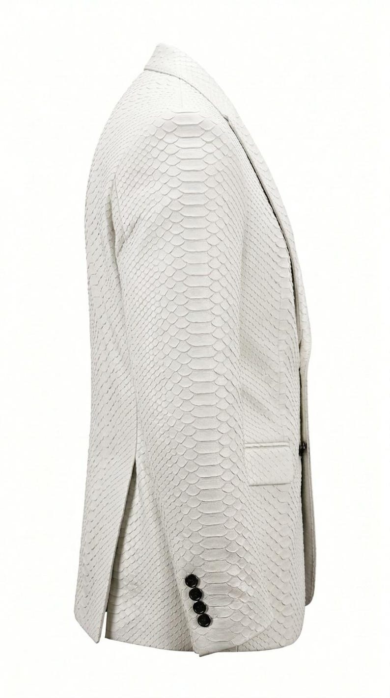 May include: A white blazer with a textured, snakeskin-like pattern. The jacket features a notched lapel, a single-breasted closure with four black buttons on the cuff, and a single pocket. The overall design is sleek and modern.